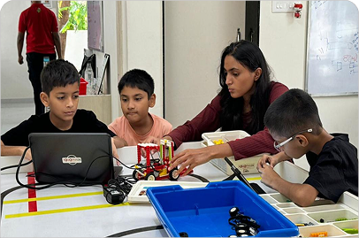 Young students building robots with a mentor in a Junior Robotics class